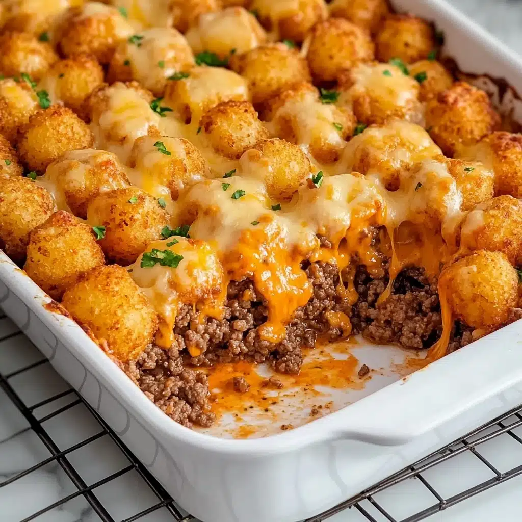 Tater Tot Casserole, easy tater tot casserole, comfort food recipes, hearty beef casserole, crispy tater tot bake A rectangular white casserole dish is filled with a baked casserole topped with many small, golden brown, crispy pieces that cover the entire surface, with melted orange cheese spread evenly over these pieces. The dish is on a metal cooling rack which sits on a white marbled surface.