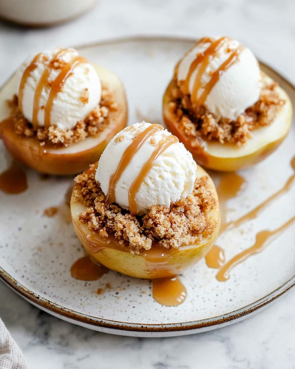 The image shows three baked apple cups placed on a white plate with a light brown rim on a white marbled surface. Each apple cup is hollowed out, filled with a crumbly topping that looks golden brown and crisp. On top of each filling sits a small scoop of white ice cream, and a thin drizzle of caramel sauce runs over the ice cream and around the plate. The caramel sauce adds a glossy texture that contrasts with the rough crumble. A woman's hand is holding the top left apple cup, highlighting the size and texture of the dessert. photo taken with an iphone --ar 4:5 --v 6.1