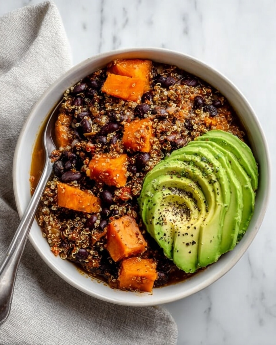 A white bowl filled with a colorful dish that has four main layers: the bottom layer is a mix of orange sweet potato chunks and black beans with a red broth, topped with a layer of cooked quinoa mixed in. Above this is a layer of sliced green avocado on one side, next to a dollop of creamy white sauce sprinkled with green chopped herbs. The top layer is scattered with thin pale yellow shredded cheese. The bowl is set on a white marbled surface with some fresh green herbs around and a small white bowl with a creamy sauce and spoon nearby. Photo taken with an iphone --ar 4:5 --v 7