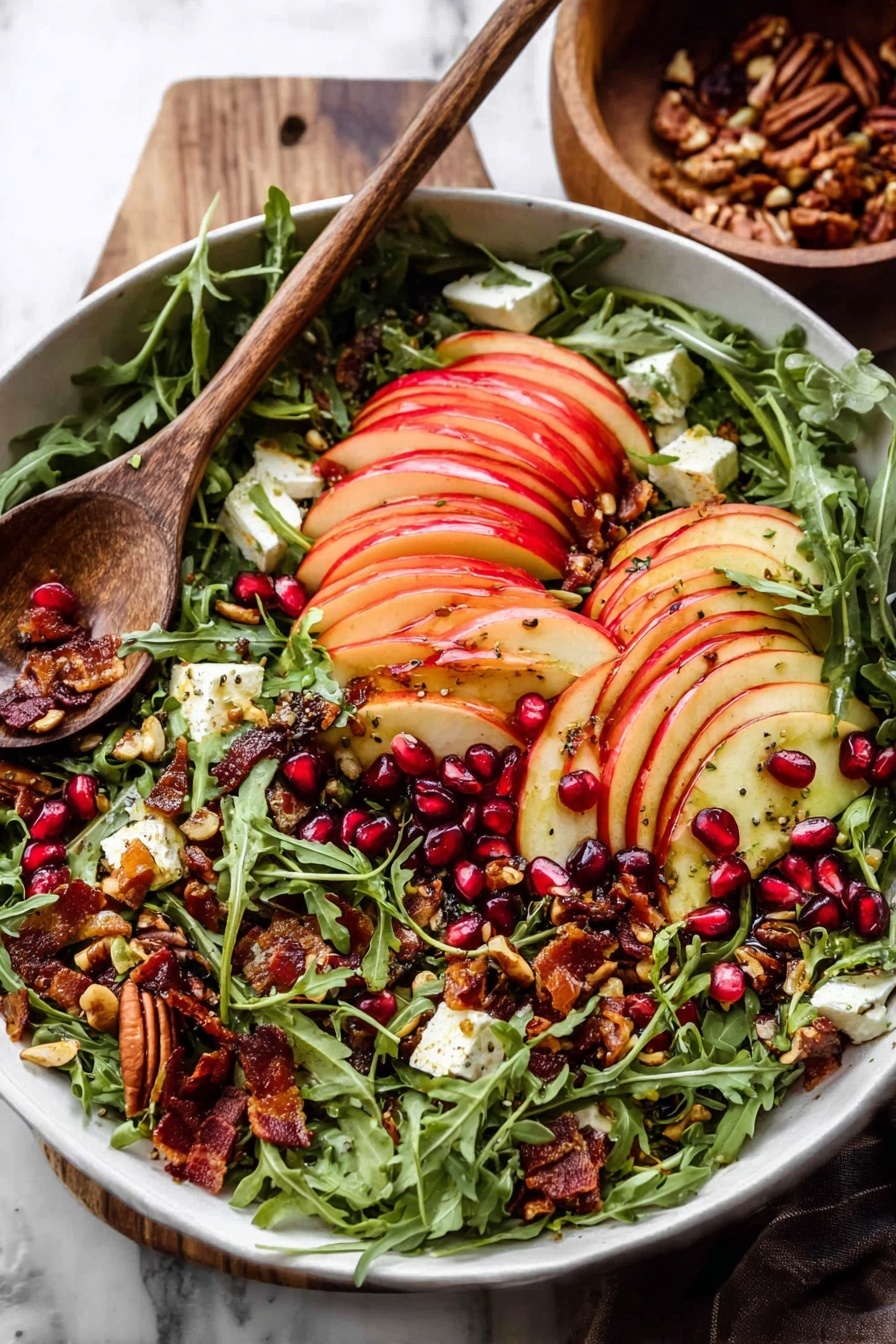 A white bowl filled with a fresh salad layered with bright green arugula leaves as the base, topped with thinly sliced red apple pieces arranged in neat rows across the top. Scattered among the arugula and apples are dark red pomegranate seeds, crunchy toasted seeds and nuts with a golden brown color, small chunks of creamy white cheese, and some crispy bacon bits with a deep reddish-brown hue. A wooden spoon rests on the side of the bowl, and the scene is set on a white marbled surface with a wooden bowl in the background. Photo taken with an iphone --ar 2:3 --v 7 - Autumn Harvest Honeycrisp Apple and Feta Salad, fall apple salad with feta and prosciutto, easy autumn apple salad recipe, seasonal Honeycrisp apple salad, healthy fall salad ideas