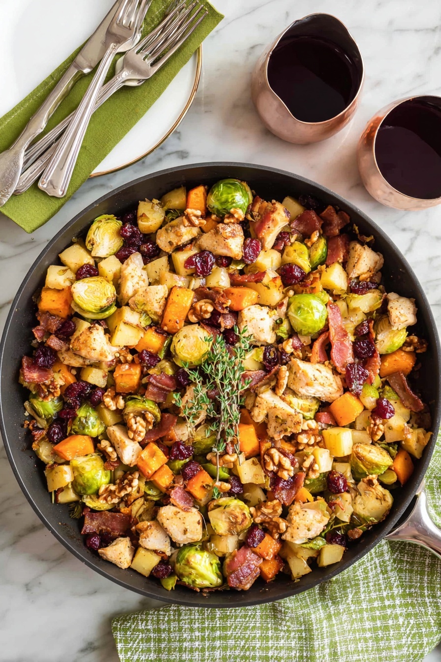A large black pan filled with a colorful mix of cooked ingredients sits on a white marbled surface with a green cloth and fork on the left. The mix has three main layers: a base of cubed orange sweet potatoes, light yellow apple pieces, and halved green Brussels sprouts; a middle layer of beige chicken pieces and crispy, dark brown bacon bits; and a top layer of whole walnuts and dried dark red cranberries. A small sprig of fresh green thyme rests on top, and a wooden spoon leans inside the pan from the right side. Two glasses filled with dark red wine are placed nearby on the white marbled surface, with one glass partially reflected on a shiny black bowl. photo taken with an iphone --ar 2:3 --v 7 - One-Pot Easy Harvest Chicken Skillet, autumn chicken skillet, healthy one-pan chicken dinner, easy fall chicken recipes, cozy weeknight chicken meal