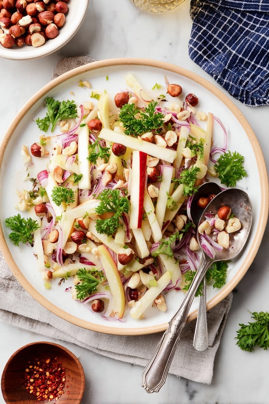 The image shows a white plate filled with a fresh salad consisting of thin, pale yellow sticks of apple with red skin edges, thin slices of purple-red onion bent softly, and scattered small whole brown hazelnuts along with some halved ones. Bright green parsley leaves are sprinkled on top, adding color contrast. A silver spoon and fork rest on the right side of the plate, partly on the salad. The plate is set on a white marbled surface. photo taken with an iphone --ar 2:3 --v 7 - Kohlrabi Slaw with Apples and Hazelnuts, crunchy healthy salad, easy vegetable slaw recipes, fresh apple kohlrabi salad, nutty summer slaw