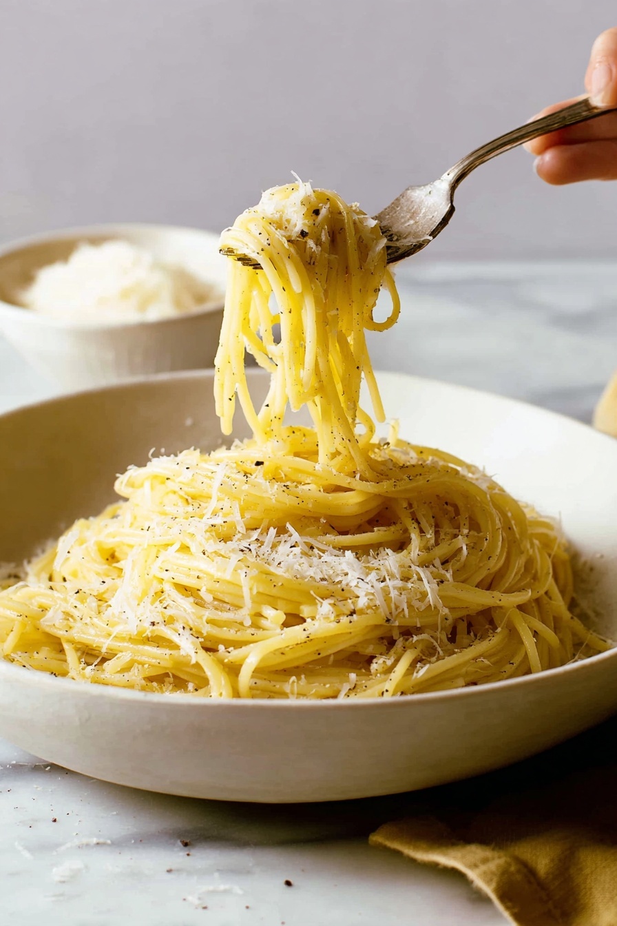 A white, shallow bowl filled with a pile of yellowish spaghetti pasta, sprinkled with small patches of grated white cheese and black pepper. The pasta strands have a smooth and slightly shiny texture, twisted around a silver fork that a woman's hand is lifting from the bowl. The background and surface around the bowl have a white marbled texture, with a blurred white bowl of grated cheese in the back left side. The scene is softly lit, showing a warm and cozy feel. photo taken with an iphone --ar 2:3 --v 7 - Cacio e Pepe Pasta, Cacio e Pepe, simple Roman pasta, creamy black pepper pasta, quick Italian pasta recipes