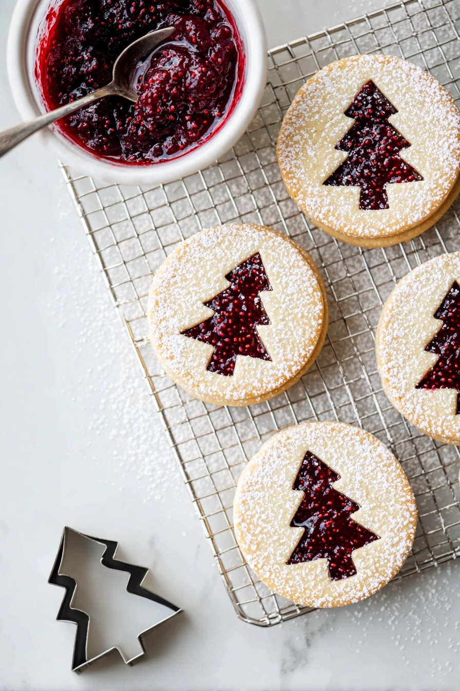 The image shows a cooling rack on a white marbled surface with four round layered cookies arranged on it and nearby. Each cookie has two layers: a light beige cookie base on the bottom, a layer of deep red raspberry jam in the middle, and a top cookie layer with a Christmas tree shape cut out, revealing the jam below. The top layer is dusted with white powdered sugar, creating a delicate snowy look. To the left of the rack is a small white bowl filled with thick, dark red raspberry jam with visible seeds, and a silver spoon inside. Near the bottom left corner, there is a small metal cookie cutter in the shape of a Christmas tree. photo taken with an iphone --ar 2:3 --v 7 - Raspberry Linzer Cookies, Linzer Cookies with Raspberry Jam, Easy Raspberry Jam Cookies, Butter Cookies with Raspberry Filling, Festive Raspberry Cookies