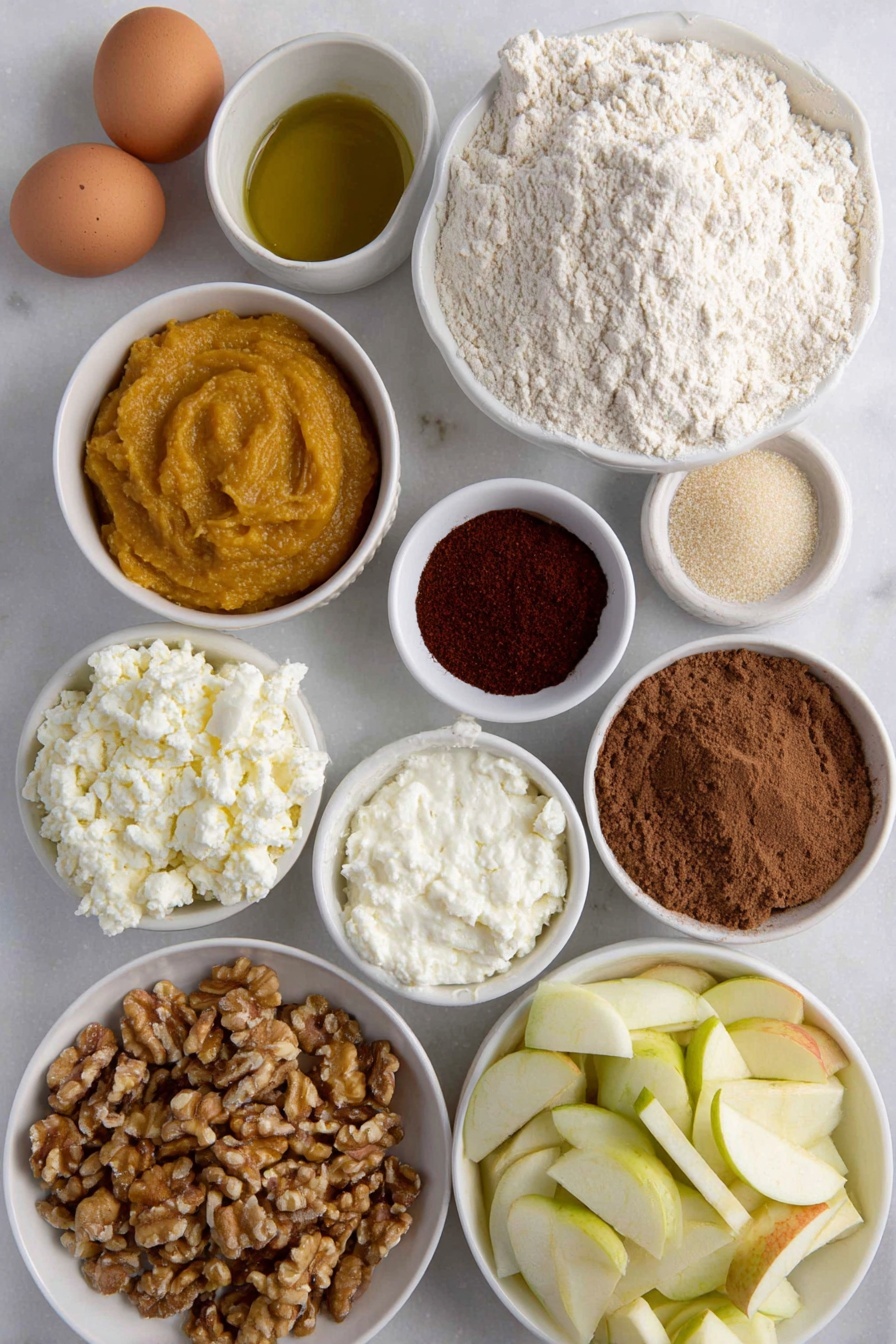 Flat lay of fresh all purpose flour in a small mound, a few brown eggs with smooth uncracked shells, a glistening golden olive oil pool in a small white ceramic bowl, vibrant orange pumpkin puree in a small white bowl, creamy white ricotta cheese dollop in a small white bowl, finely grated pale parmesan cheese in a small white bowl, rustic brown sugar crystals in a small white bowl, ground cinnamon and allspice powders gently mounded side by side, bright red cayenne powder in a small white bowl, lightly cracked black pepper powder, a handful of fresh bright green sage leaves, diced Gala apple pieces showing red and cream hues in a small white bowl, small white bowl with pale apple cider vinegar, chopped walnuts with rough textured surface in a small white bowl, fresh uncooked sheet of pale ravioli dough laid flat with clean edges — no utensils or packaging, all ingredients arranged with perfect symmetry on a clean white marble surface, soft natural light, photo taken with an iPhone, professional food photography style, fresh ingredients, white ceramic bowls, no bottles, no duplicates, no utensils, no packaging --ar 2:3 --v 7 --p m7354615311229779997 - Pumpkin Ravioli with Apple Sage Butter, pumpkin ravioli recipe, fall pasta dishes, homemade ravioli ideas, seasonal pumpkin pasta