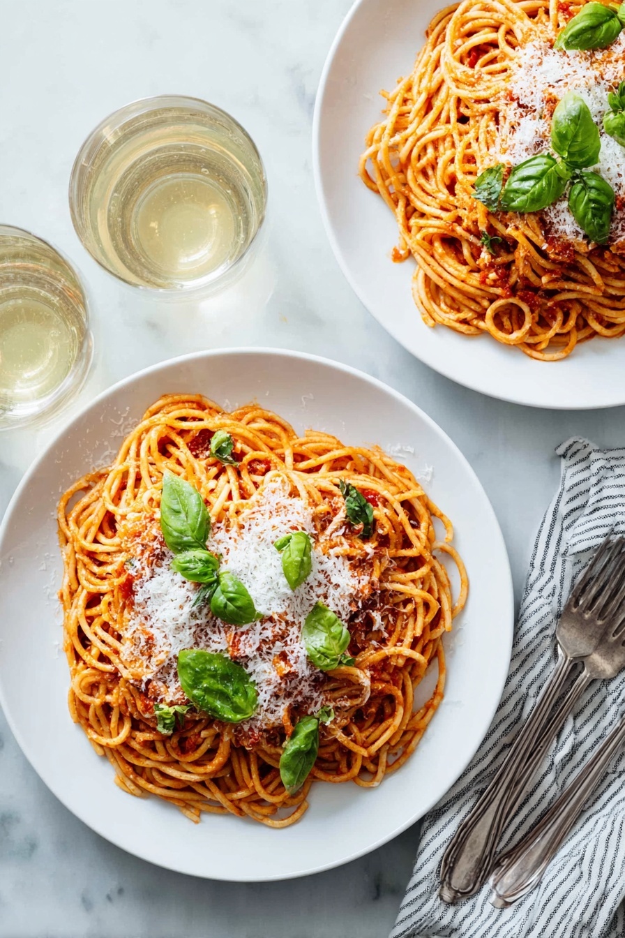 Two white plates with round shapes, each holding a serving of spaghetti layered with red tomato sauce, topped with a layer of white grated cheese and scattered green basil leaves. The spaghetti is twisted into small nests that fill most of the plate. Near the plates are two forks resting on a white and blue striped cloth napkin, and two almost full glasses of white wine are seen in the top left corner. Everything is set on a white marbled table surface. photo taken with an iphone --ar 2:3 --v 7 - Easy Tomato Pasta with Fresh Basil, Tomato Pasta with Fresh Basil, Homemade Tomato Pasta, Simple Italian Pasta, Fresh Basil Pasta