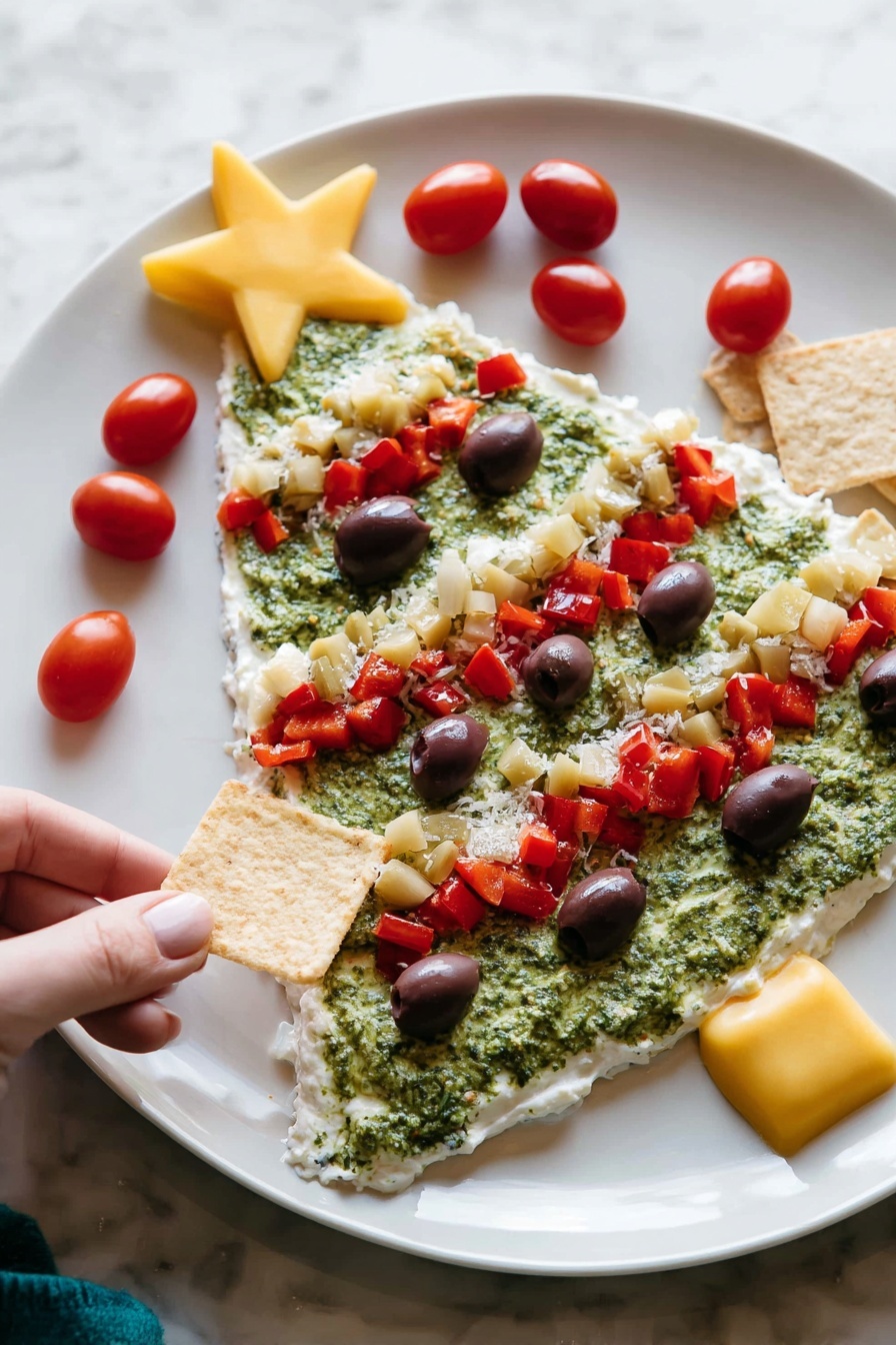 The image shows a white plate with a Christmas tree-shaped layered dip. The first layer is a smooth, white creamy base covering the entire tree shape. The second layer is a rough, green spread resembling pesto, filling most of the tree shape except the edges. On top, there are several red diced pepper pieces forming three diagonal lines across the tree. Small dark purple olive slices are scattered evenly over the green layer. There are small chunks of pale yellow artichoke hearts mixed in with the red peppers. Bright red cherry tomatoes decorate the edges, with a large yellow star-shaped piece placed at the top of the tree. A woman's hand is holding a square chip near the plate on a white marbled surface photo taken with an iphone --ar 2:3 --v 7 - Christmas Tree Bean Dip with Pesto, festive holiday appetizer, easy Christmas dip, holiday bean dip, Christmas party snack