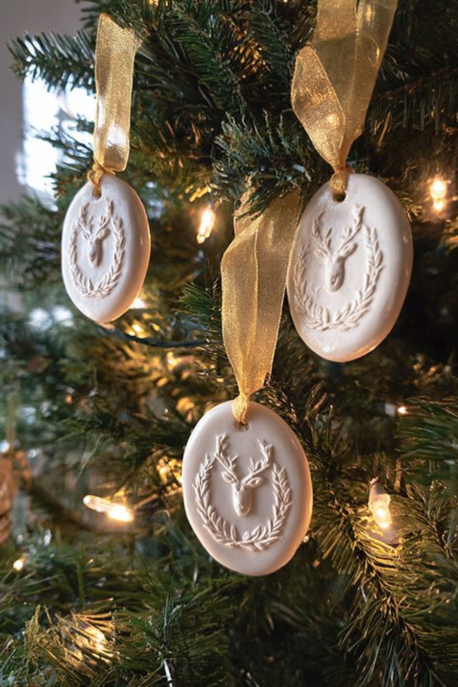 The image shows a Christmas tree decorated with three white oval ornaments, each with a raised design featuring a reindeer head surrounded by a laurel wreath. Each ornament is hung with a shiny golden ribbon tied in a simple loop. The tree has green needles with warm white string lights softly glowing around the ornaments, creating a cozy and festive look. The background is softly blurred, emphasizing the details and texture of the ornaments and the pine needles. photo taken with an iphone --ar 2:3 --v 7 - Springerle Cookie, Springerle Cookie Recipe, German Springerle Cookies, embossed cookies with traditional pattern, anise flavored German cookies