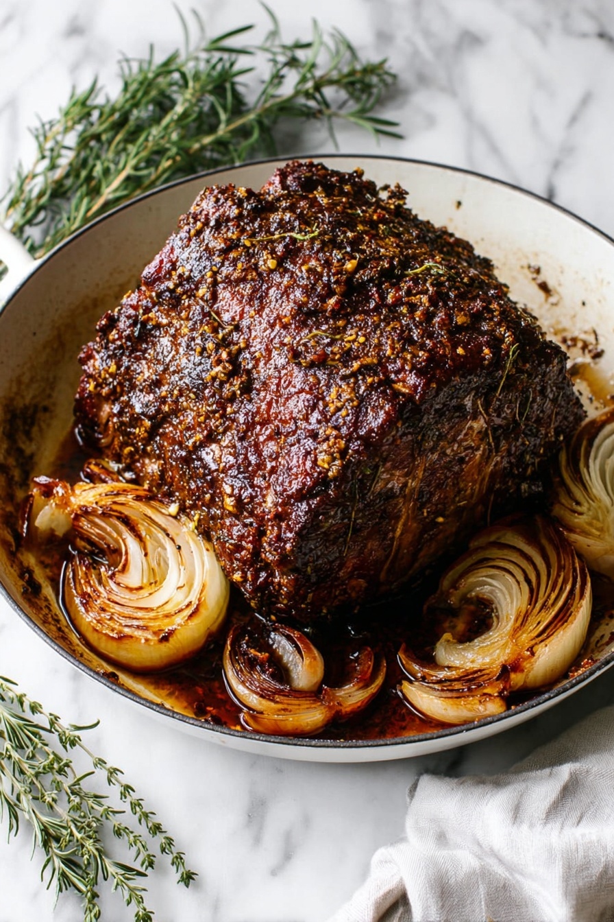 A large, thick piece of roasted meat with a dark brown, crispy, and textured crust sits in the center of a white skillet. The meat’s surface is covered in a spice and herb crust that adds a bumpy texture, with a shiny glaze reflecting light. Surrounding the meat in the pan are several roasted onion halves with caramelized, golden brown layers curling slightly from the heat. The skillet rests on a white marbled surface, with green sprigs of rosemary and thyme arranged beside it, and a white cloth napkin partially visible in the corner. Photo taken with an iphone --ar 2:3 --v 7 - Best No-Fail Garlic Herb Prime Rib, prime rib cooking tips, garlic herb roast, how to cook perfect prime rib, holiday prime rib recipe