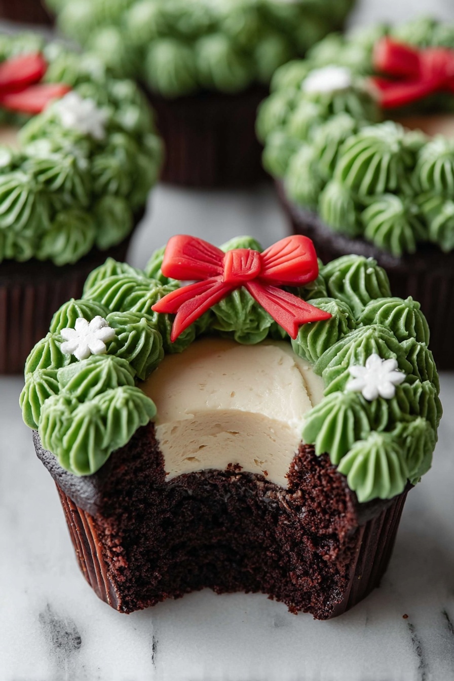 A chocolate cupcake with three visible layers is shown on a white marbled surface. The bottom layer is dark, moist chocolate cake, the middle layer is a smooth light cream filling, and the top layer is decorated with green frosting piped to look like leaves forming a wreath around the cream. A small red bow made of fondant sits at the top center of the green wreath, and tiny white flower-shaped decorations are placed on the green frosting. The cupcake is partially eaten, showing the inside layers clearly. Other similar cupcakes are blurred in the background. Photo taken with an iphone --ar 2:3 --v 7 - Chocolate Wreath Cupcakes with Buttercream Frosting, festive cupcake decorating ideas, holiday chocolate cupcake recipe, easy Christmas cupcake decorations, party-worthy chocolate cupcakes