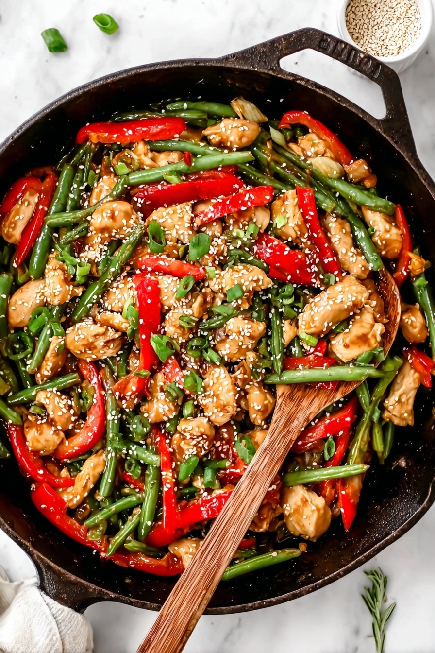 A black cast iron pan filled with a colorful stir-fry showing three main layers: the base layer has shiny, green beans with a fresh texture spread all around; the middle layer has bright red sliced bell pepper strips adding a pop of color mixed evenly; the top layer contains chunks of light brown cooked chicken pieces sprinkled with white sesame seeds and chopped green onions, giving it a fresh and textured look. On the right side, a wooden spoon with a natural grain rests inside the pan, partly covered by the food. The whole scene is set on a white marbled surface with a small white bowl of sesame seeds and a green herb sprig partially visible. Photo taken with an iphone --ar 2:3 --v 7 - Healthy Orange Chicken Stir Fry cauliflower rice, healthy orange chicken stir fry, low-carb orange chicken recipe, citrus chicken stir fry, easy healthy dinner ideas