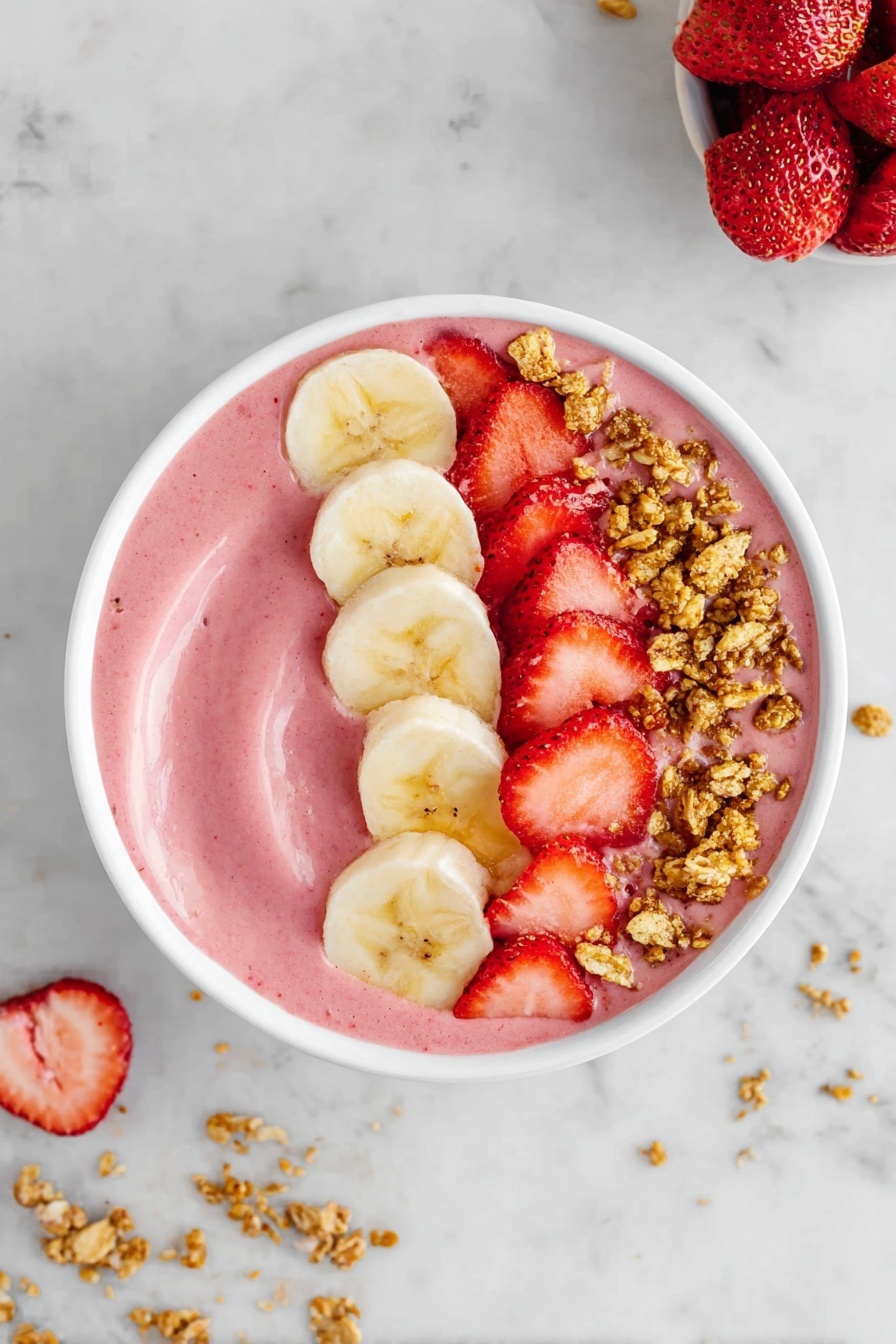The image shows a white bowl filled with a smooth pink smoothie base. On top, there are three distinct layers arranged in a half-circle: a row of light yellow banana slices on the right, a line of bright red chopped strawberries next to the bananas, and small clusters of golden brown granola scattered over the strawberries. The bowl sits on a white marbled surface with small bits of granola scattered around. Photo taken with an iphone --ar 2:3 --v 7 - Strawberry Banana Smoothie Bowl, healthy breakfast recipes, easy smoothie bowl, fruit smoothie bowl, quick breakfast ideas