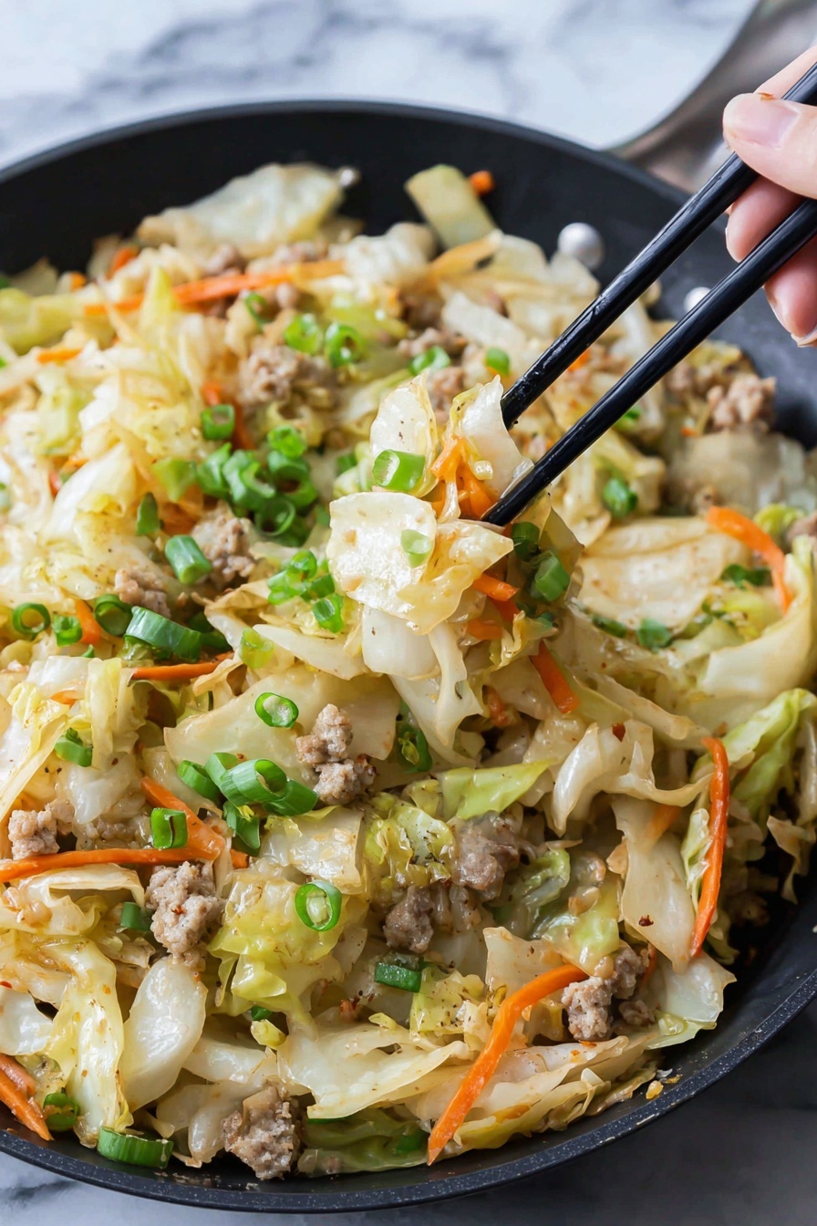 In a black pan, there is a mix of cooked cabbage pieces that are pale yellow with a soft texture, thin orange carrot strips scattered throughout, and small light brown cooked meat bits. On top, bright green chopped scallions add freshness. A woman's hand holds black chopsticks lifting a portion showing these layers clearly. The food looks slightly shiny as if lightly cooked with seasoning. The background surface is white marbled texture. photo taken with an iphone --ar 2:3 --v 7 - Egg Roll in a Bowl Stir-Fry, egg roll in a bowl, healthy egg roll bowl, quick stir-fry recipes, Asian-inspired skillet dinner